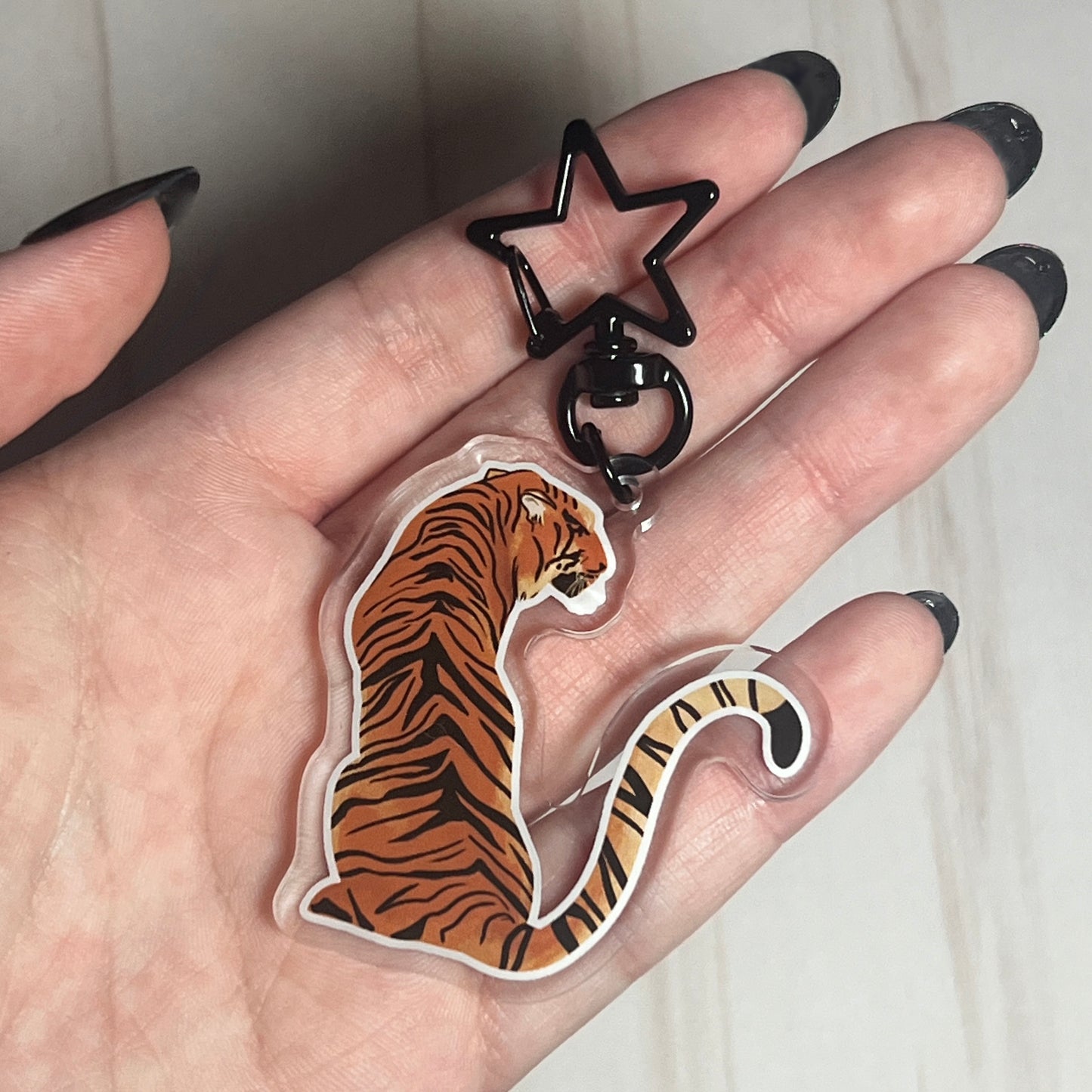 Hand holding a tiger-shaped keychain with a star-shaped keyring.